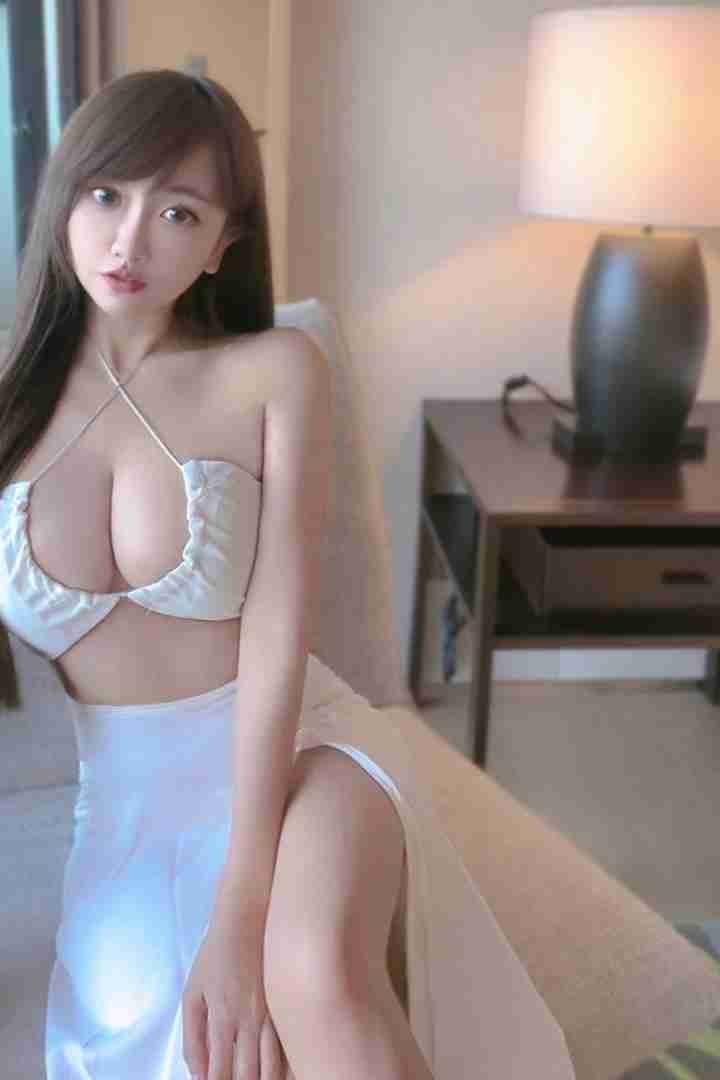 Malay Escort Girl Woman in white halter top and skirt posing indoors.