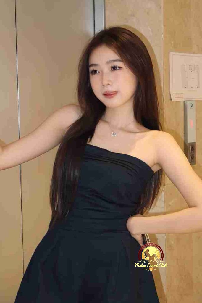 Beautiful Asian woman in strapless black dress posing in elevator with long dark hair and necklace.