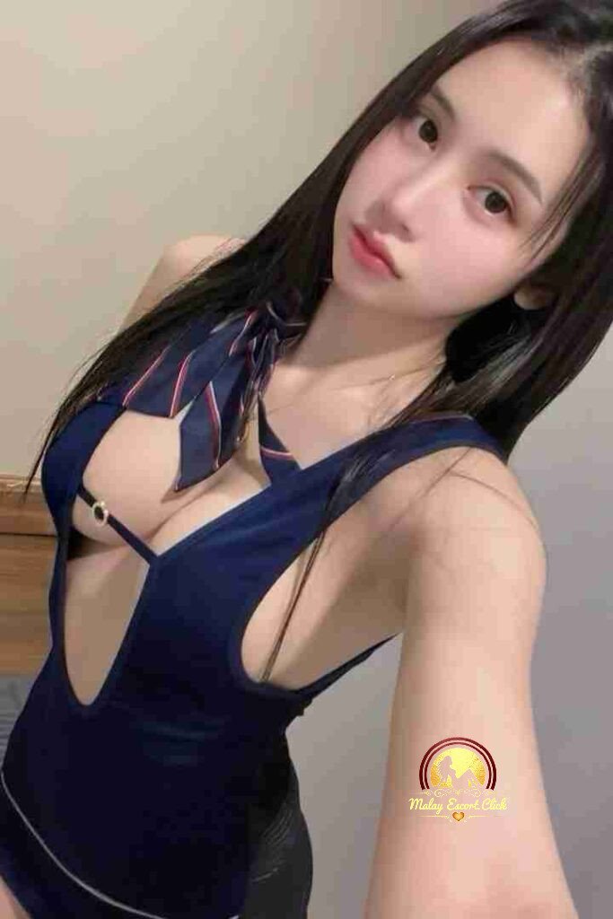 Malay Escort Girl Asian woman in a lacy top, posing near a cafe sign. Includes "Review us on Google, Free Brownie Cookie" text.