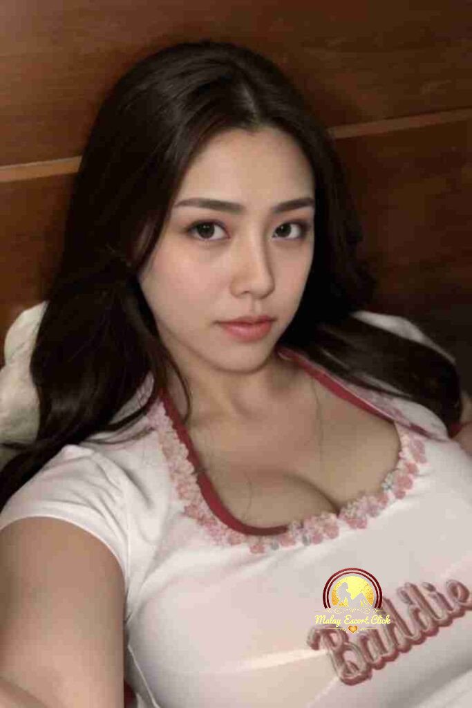 Attractive Asian woman with dark hair wearing a white top with "Baddie" text. Incall/Outcall KL Call Girl.