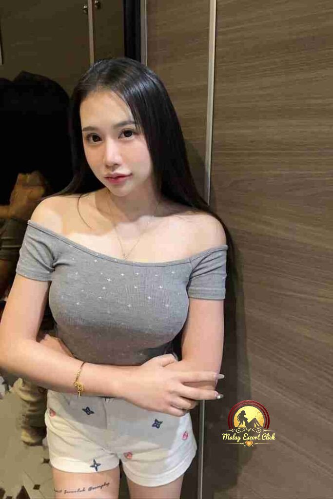 Malay Escort Girl Woman in denim bustier and jeans posing against a wall.