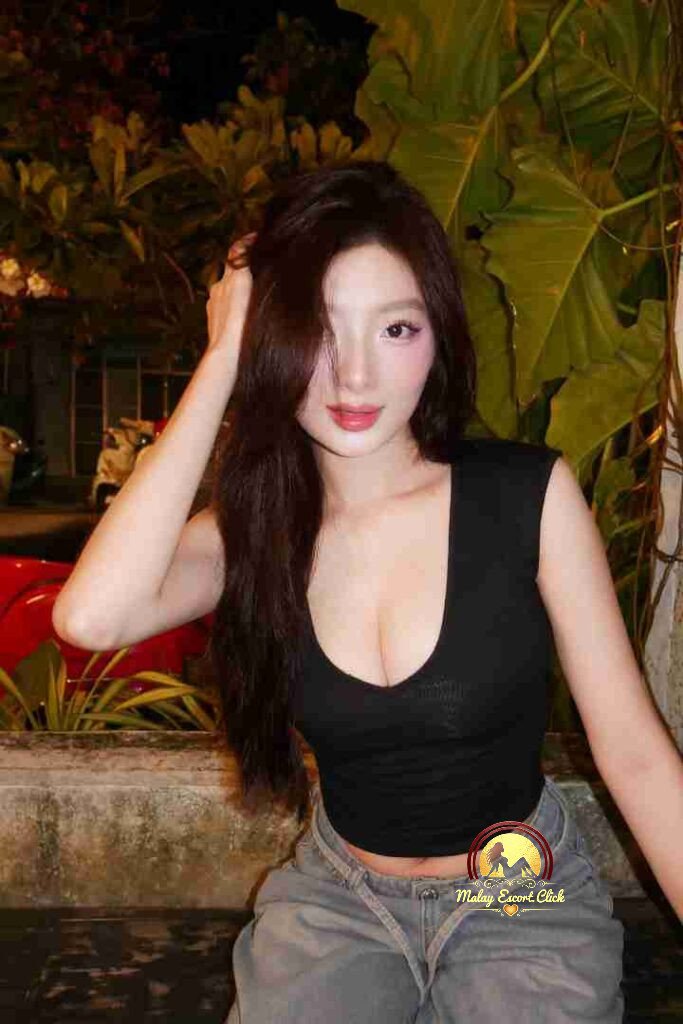 Beautiful Vietnamese woman with long brown hair in black top and jeans posing outdoors at night.