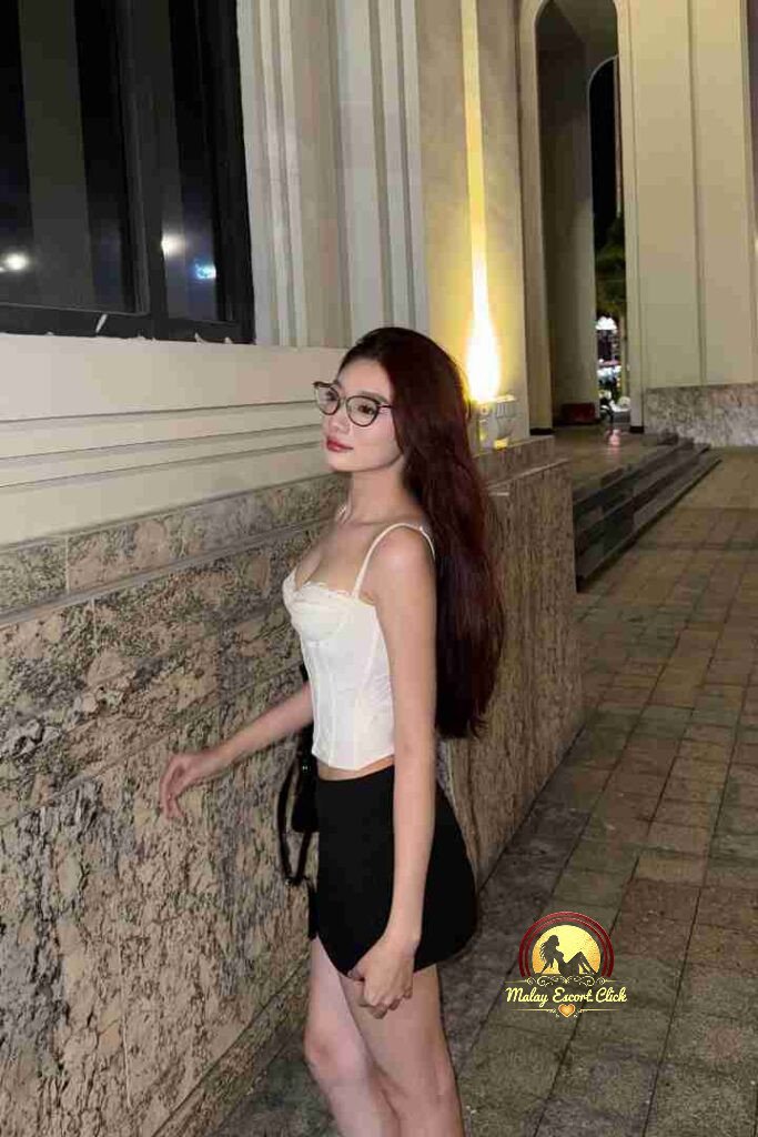 Vietnamese woman in corset and skirt, glasses, posing outdoors at night. KL Escort.