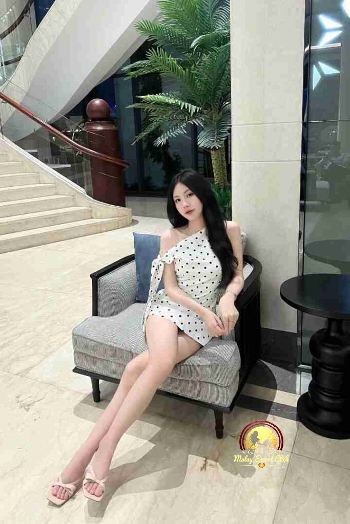 Vietnamese woman in polka dot dress sitting indoors.