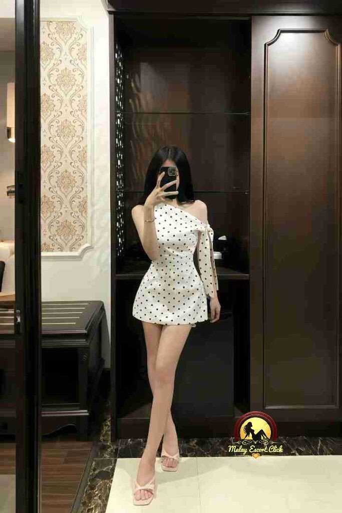 Vietnamese woman in polka dot dress taking mirror selfie. KL Escort.