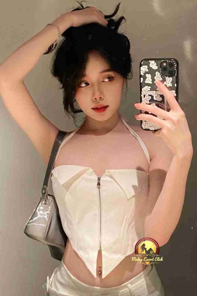 Vietnamese woman with stylish hair, white corset top, taking selfie. Elite KL escort vibe.