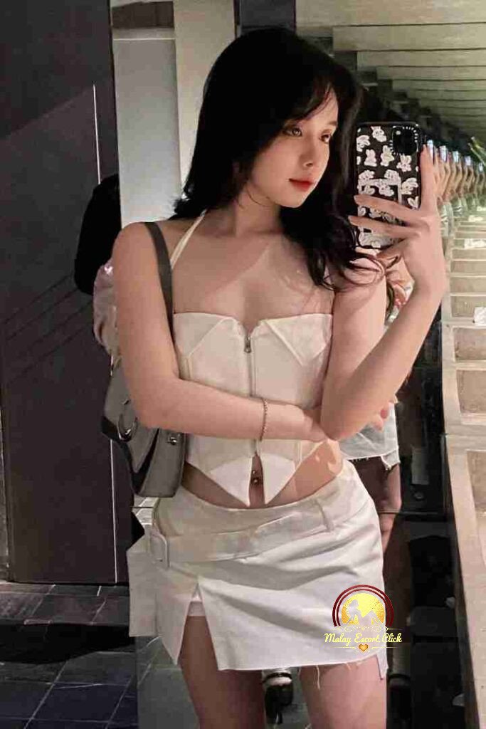 Vietnamese woman in white crop top and mini skirt taking selfie. KL escort.