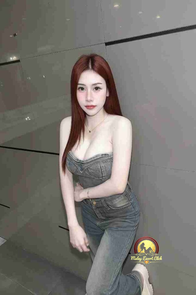 Malay Escort Girl Attractive woman in black top at outdoor cafe, holding phone. Evening ambiance.