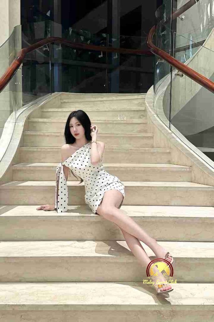 Woman in polka dot dress on stairs. Elegant pose, fashion style.